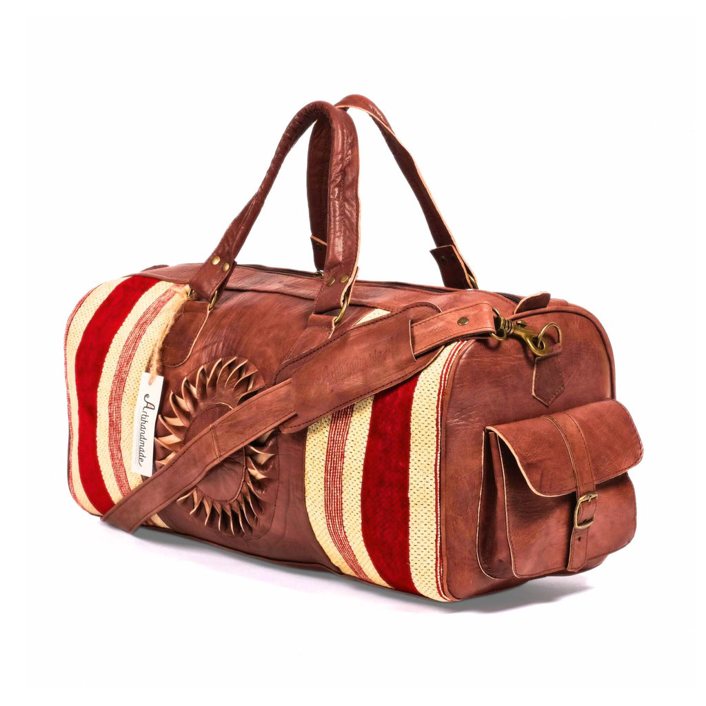 A brown leather duffle bag with dark brown accents and a striped kilim pattern on one side, featuring a traditional handcrafted design.