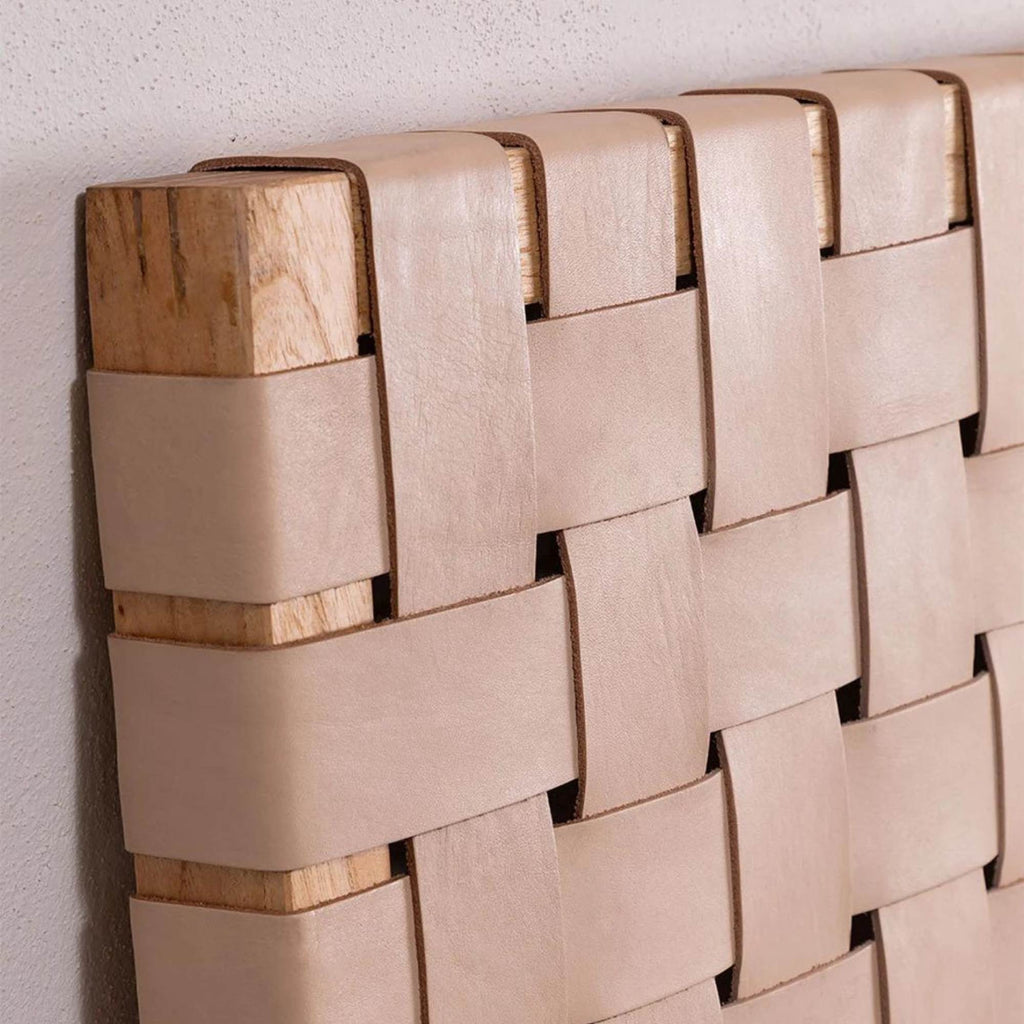 Close-up of handwoven leather strap across solid teak headboard