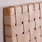Close-up of handwoven leather strap across solid teak headboard