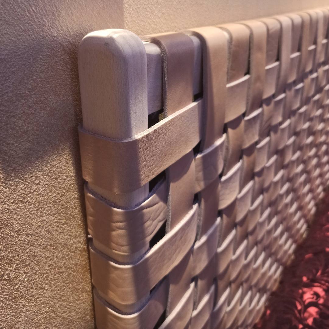 Close-up of woven straps on a handcrafted leather headboard, highlighting intricate artisanal weaving and texture.