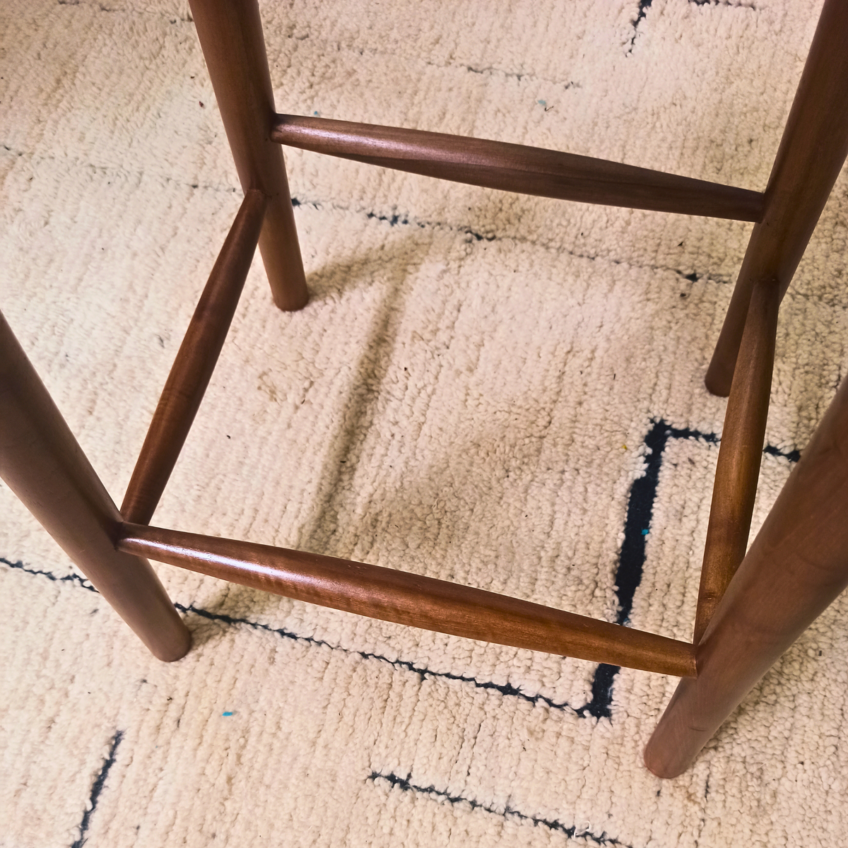 Wooden chair legs on a textured beige carpet